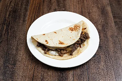 A folded flour tortilla taco filled with chopped grilled asada and onions.