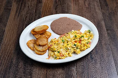 Eggs scrambled with tomato, onion and green chile on an oval plate, with fried potato rounds and refried beans.