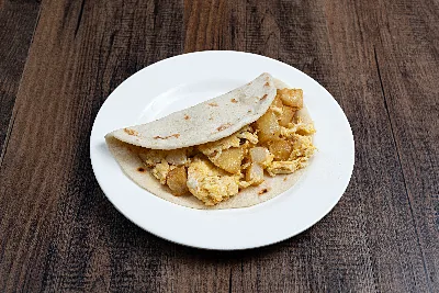 A folded flour tortilla taco filled with fried potato and scrambled egg.