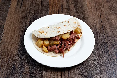 A folded flour tortilla taco filled with diced potato and crumbled sausage.