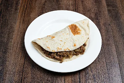 A folded flour tortilla taco filled with seasoned ground beef picadillo.