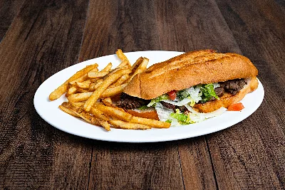 A torta on a toasted roll filled with meat, lettuce and tomato, plated alongside French fries.
